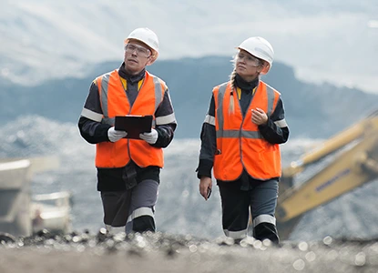 two mining worker wearing safety vests and helmets